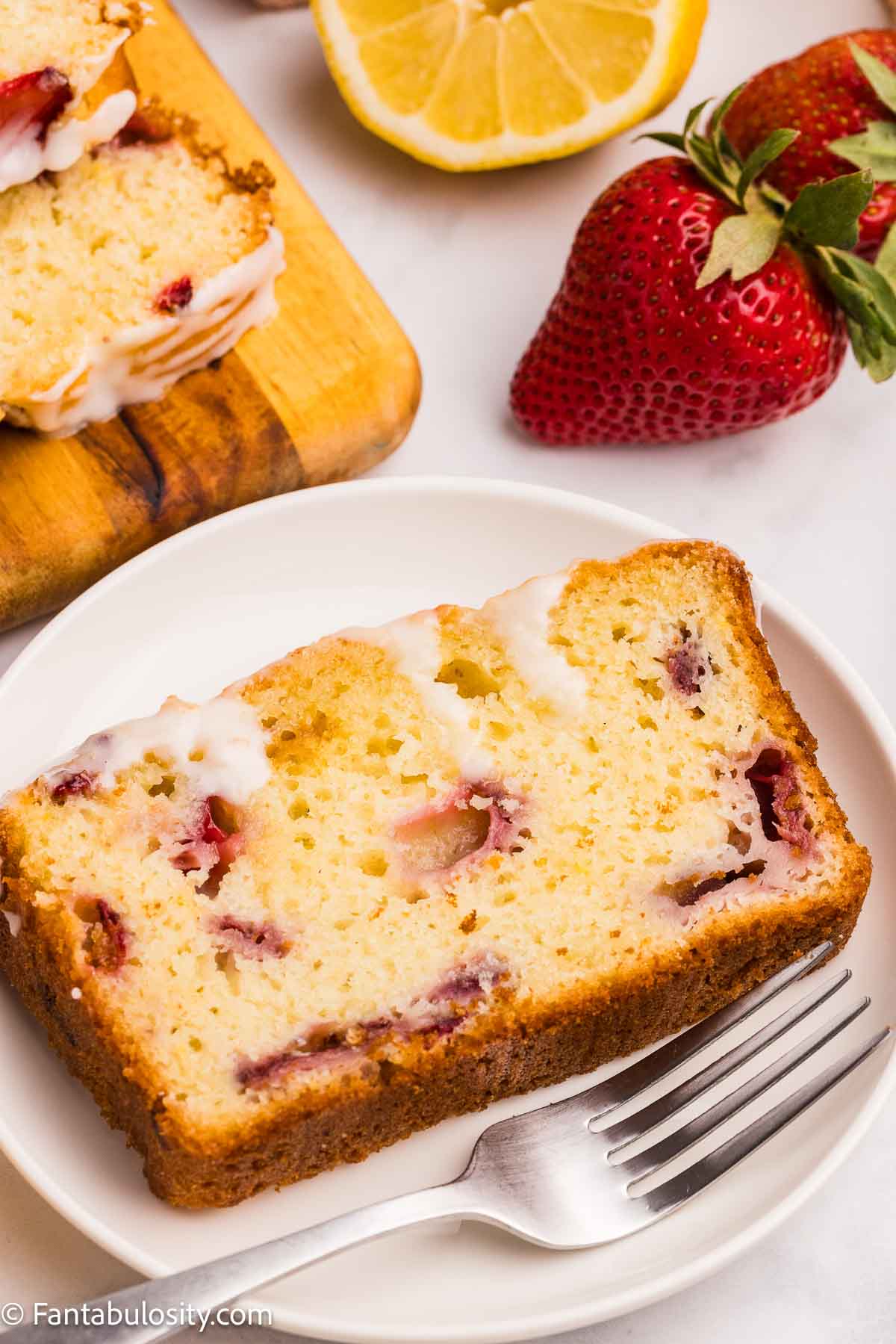 Sliced piece of strawberry lemonade bread on a plate, next to a fork.