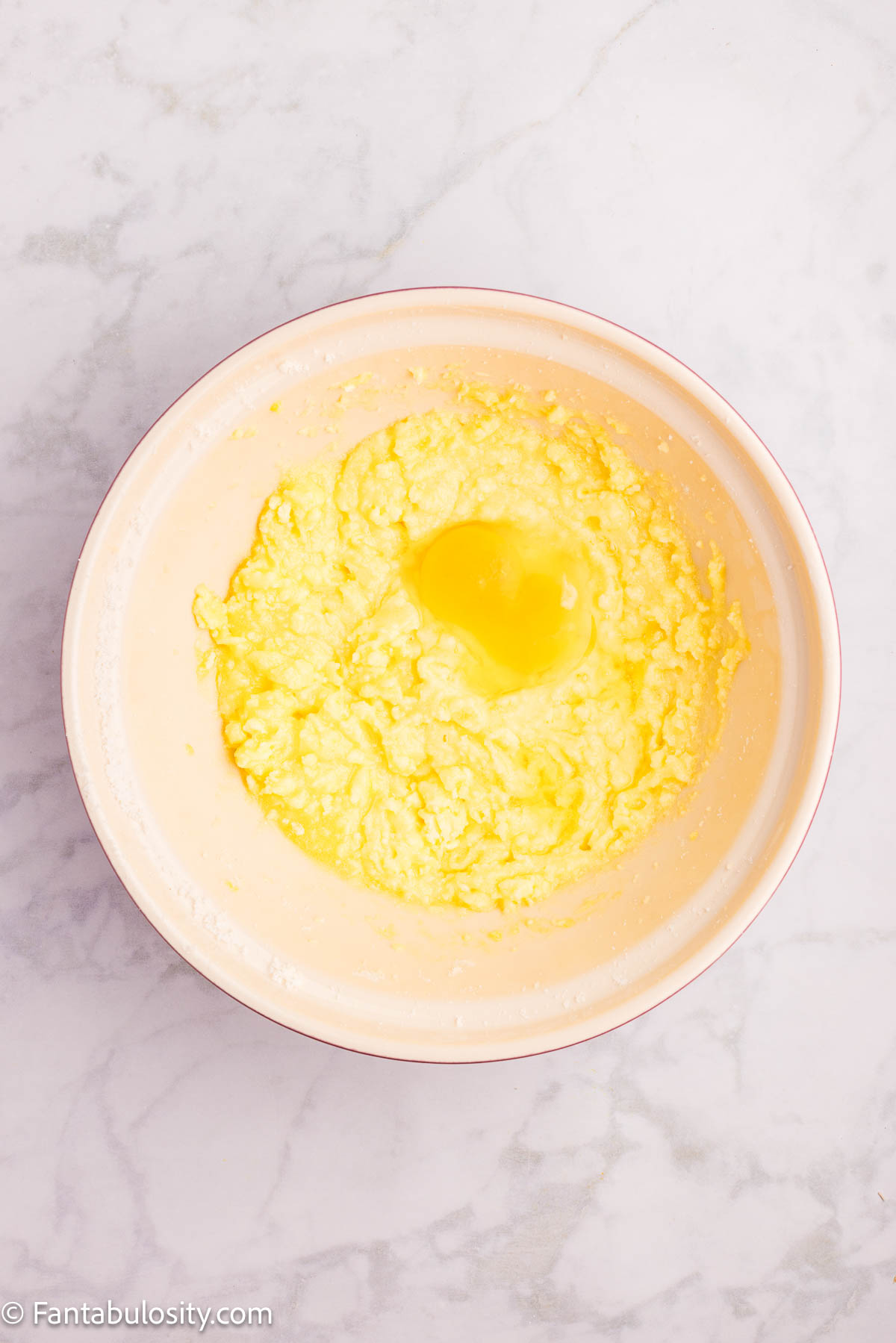 Eggs added to sugar and butter mixture in mixing bowl.
