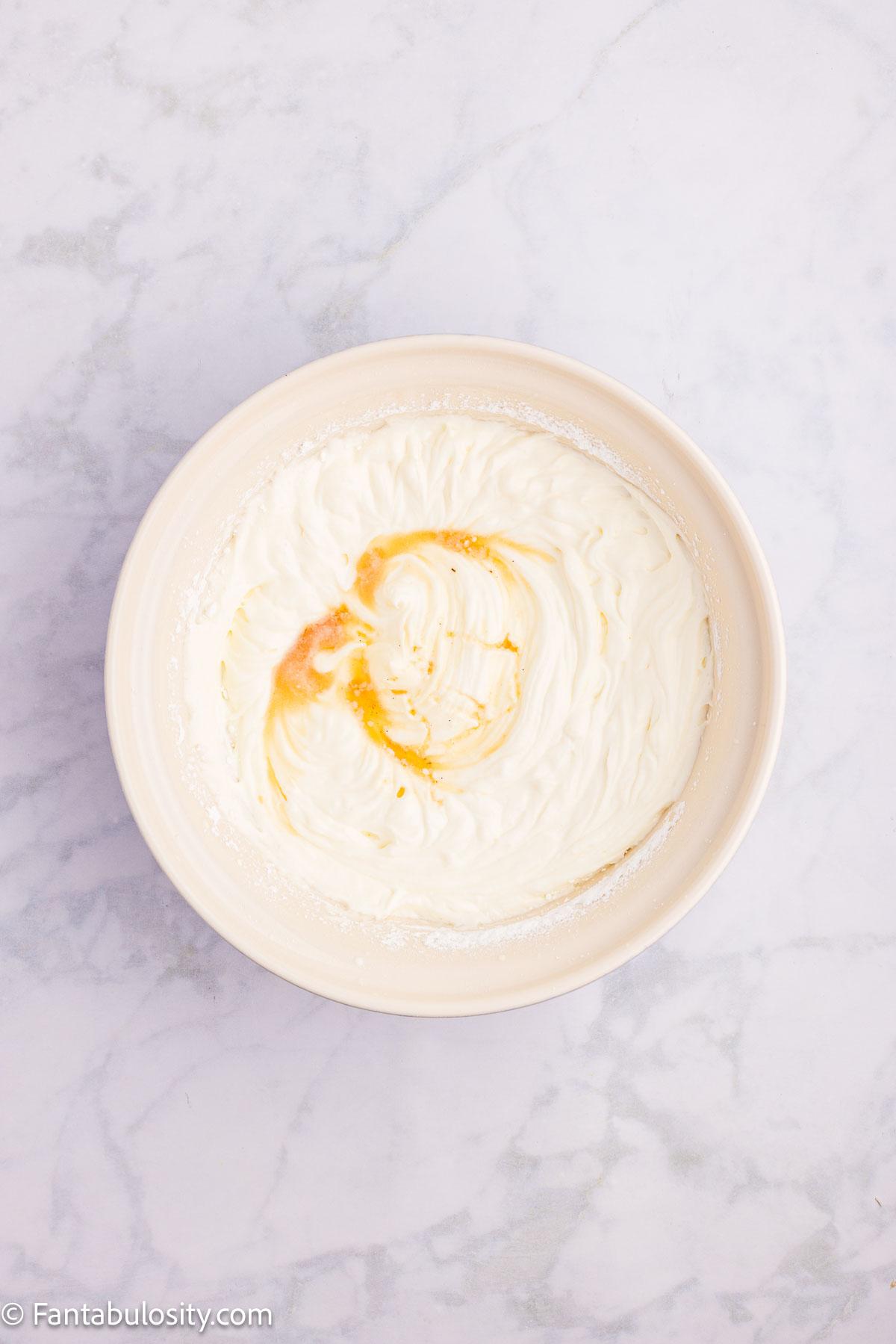 Heavy whipping cream and vanilla in mixing bowl.