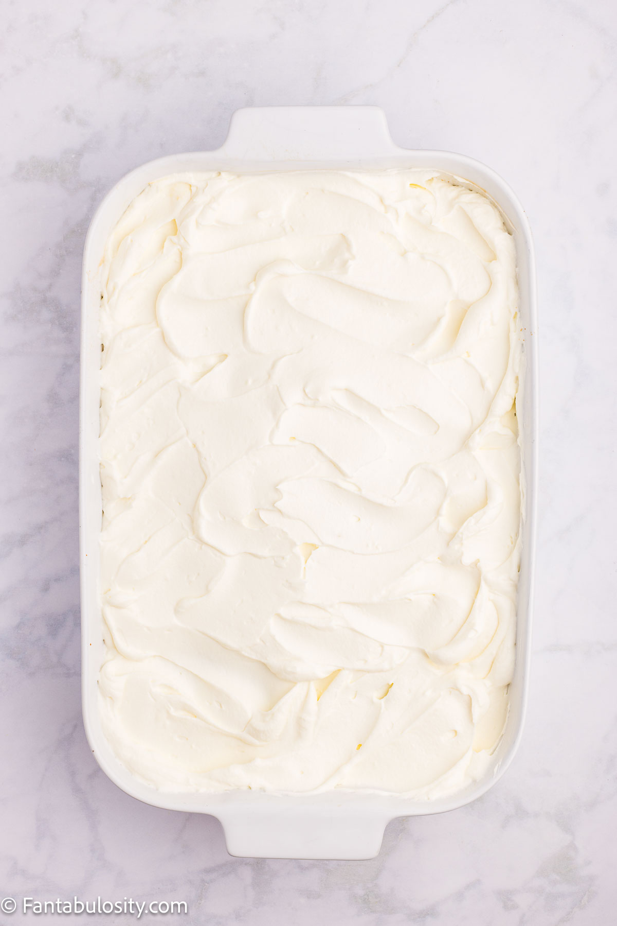 Cream cheese whipped cream spread on baked cake.