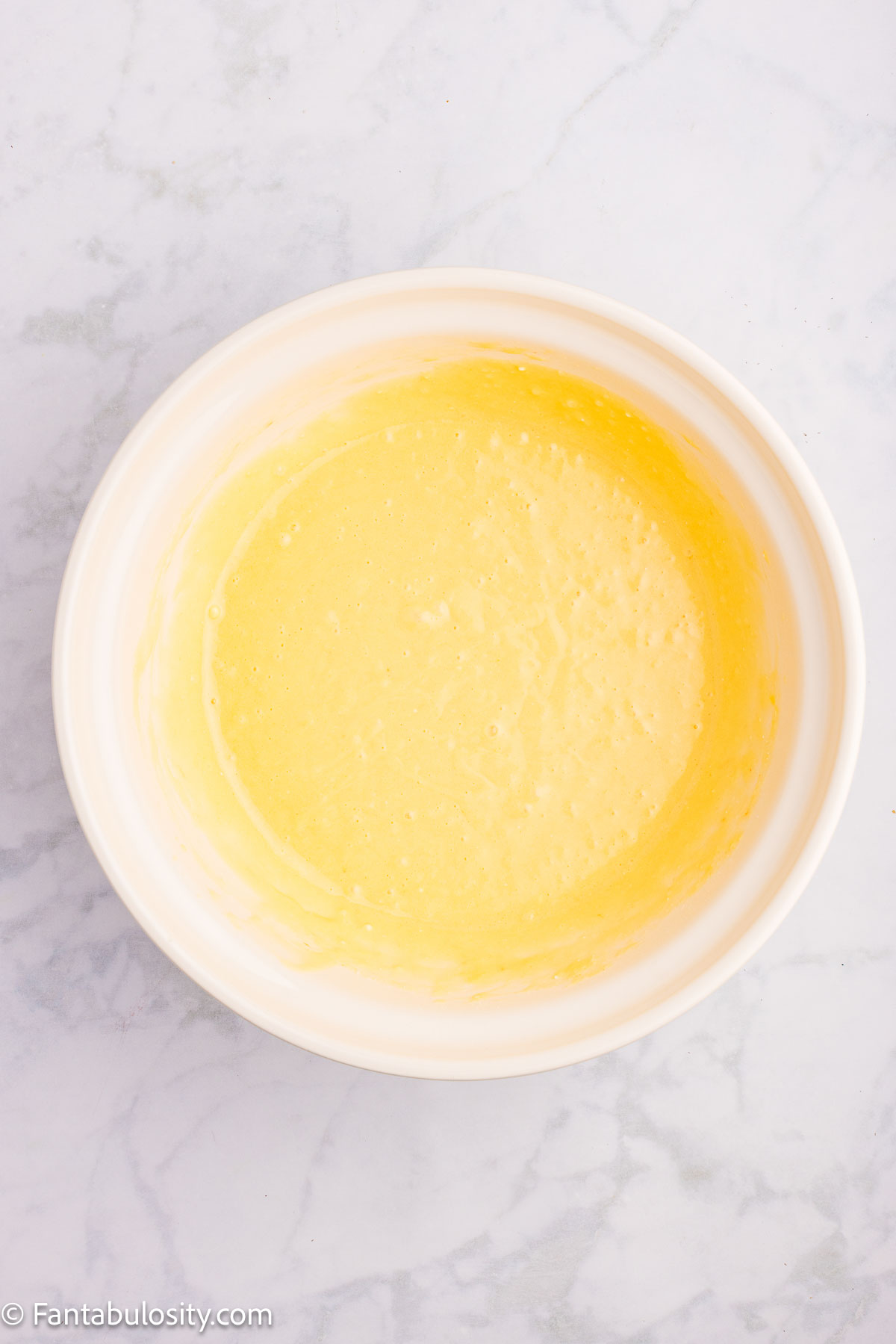 Yellow cake mix, oil and eggs mixed together in mixing bowl.