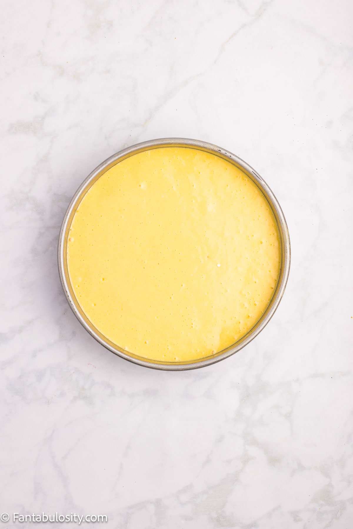 Cake batter poured over strawberries in cake pan. 