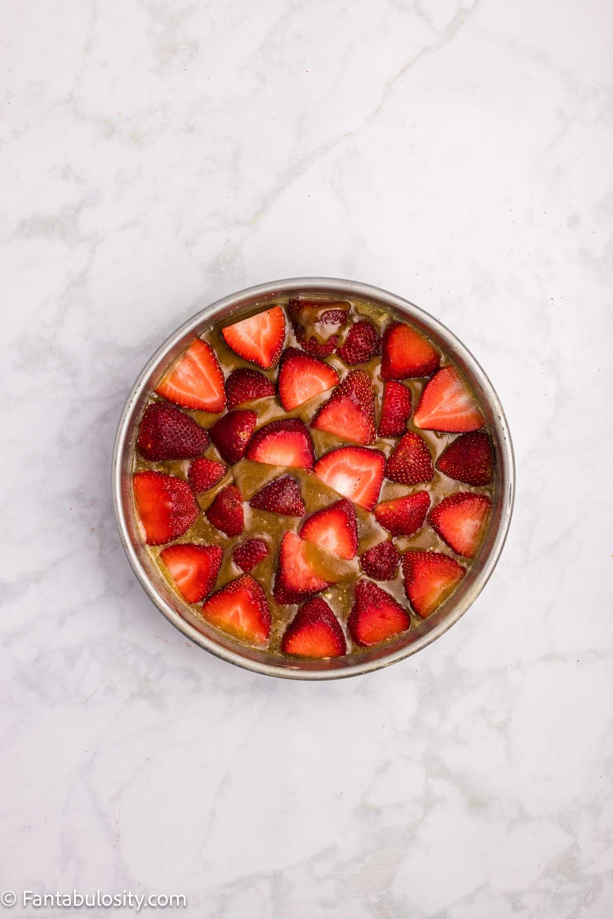 Strawberries added on top of brown sugar mixture in cake pan.