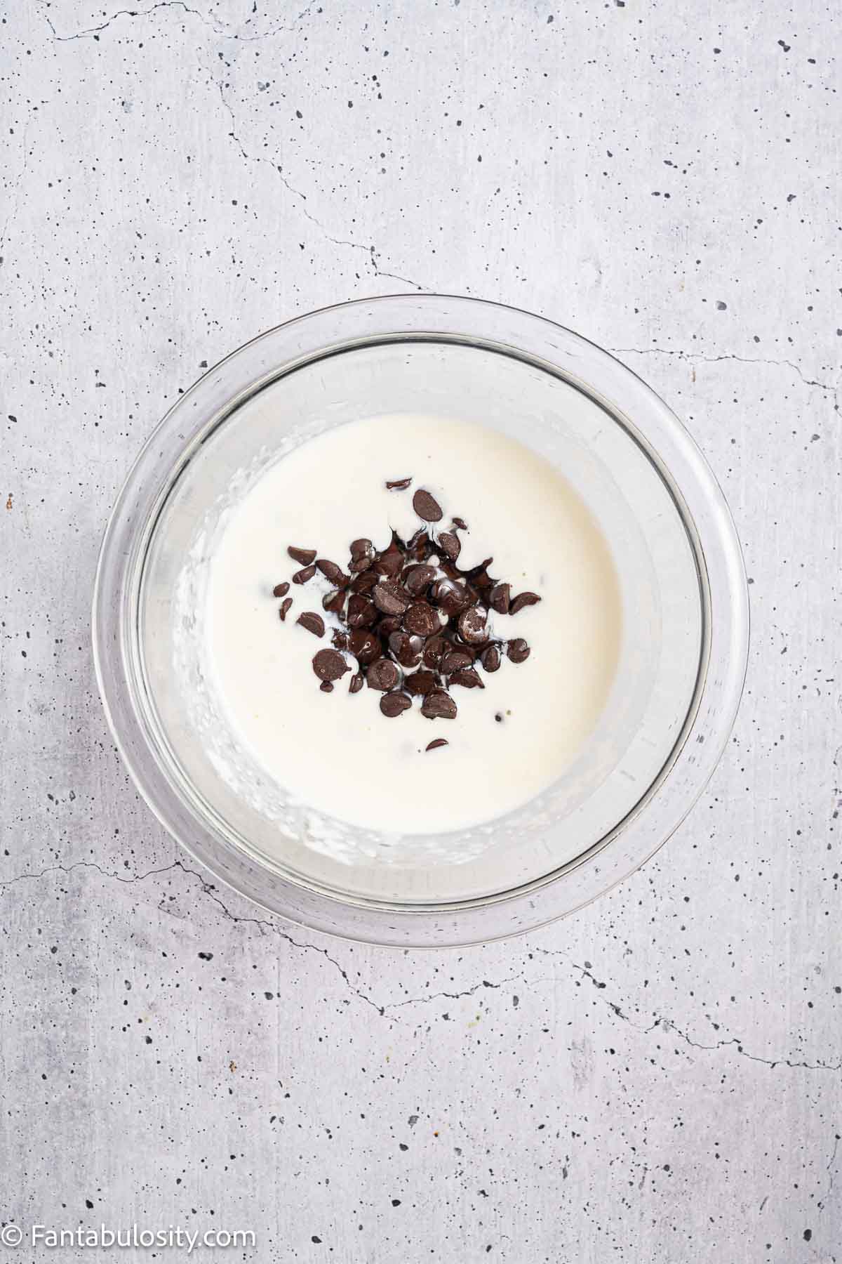 Hot milk with chocolate chips in mixing bowl.