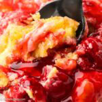 Cherry cheesecake dump cake being scooped out of a dish.