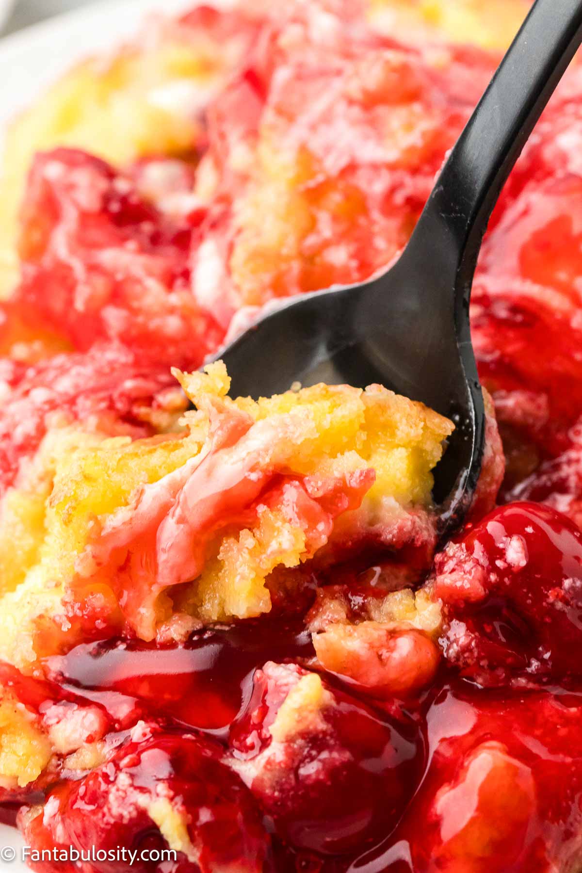 Cherry cheesecake dump cake being scooped up by spoon.