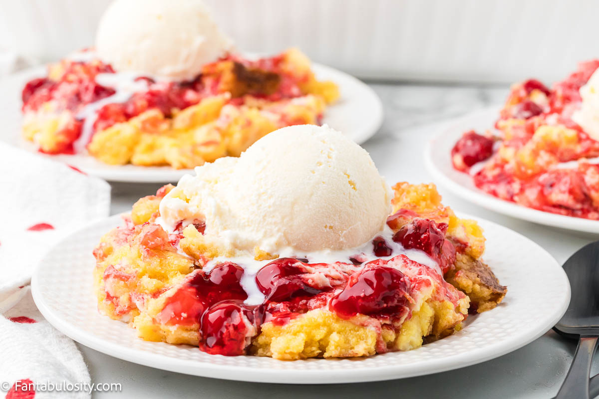 A scoop of vanilla ice cream on top of cherry cheesecake dump cake.