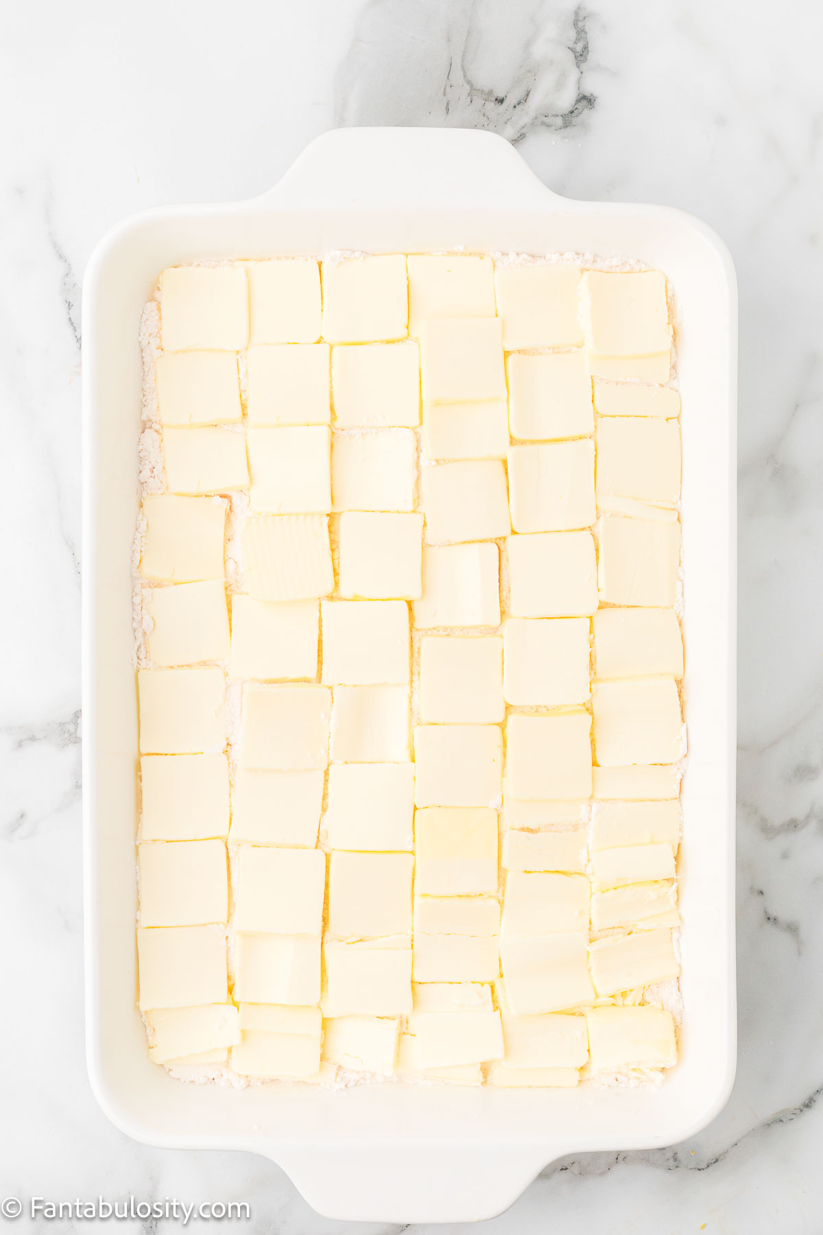Butter squares layered on top of cake mix for cherry cheesecake dump cake.