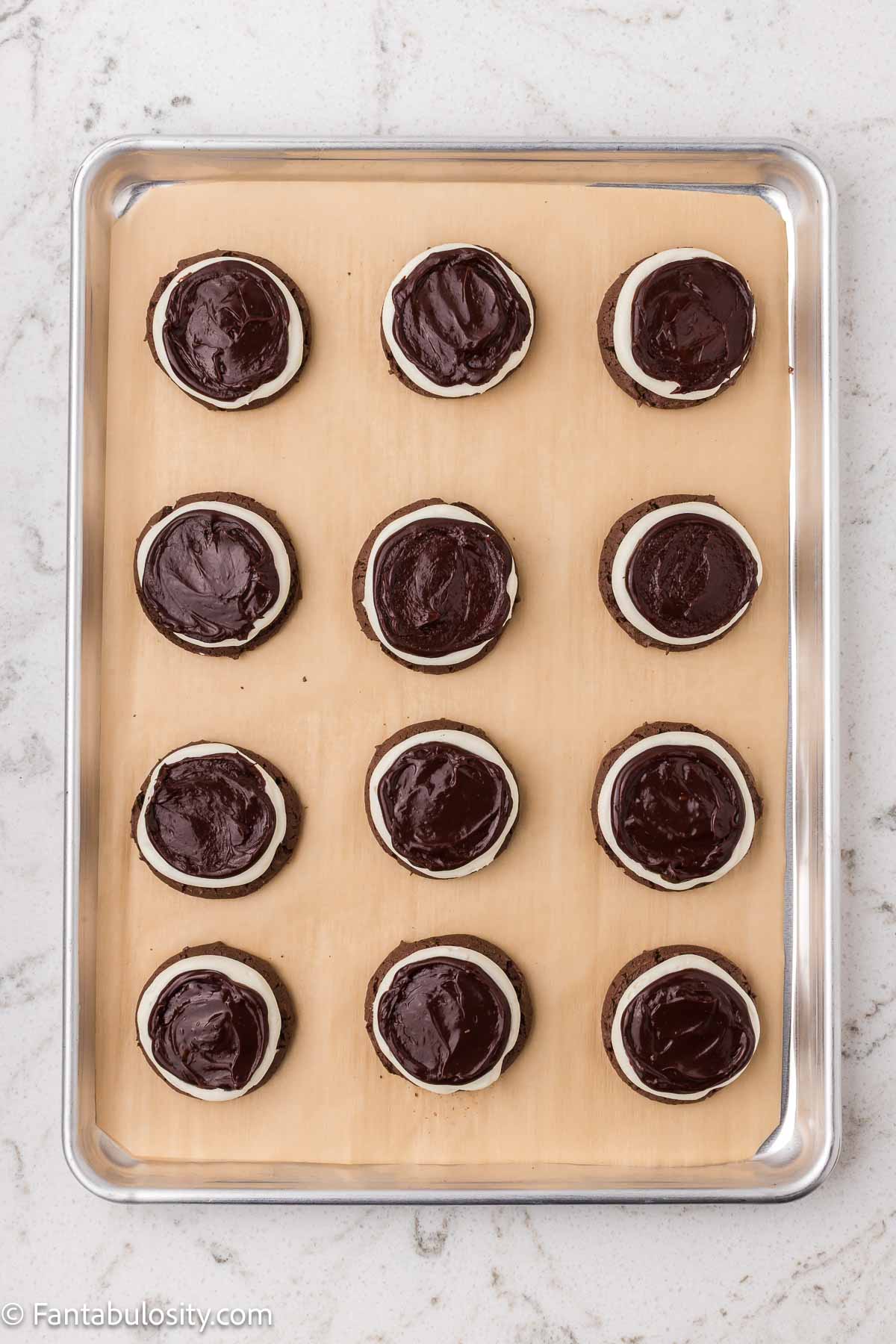 Chocolate ganache spooned on top of marshmallow filling for cookies.