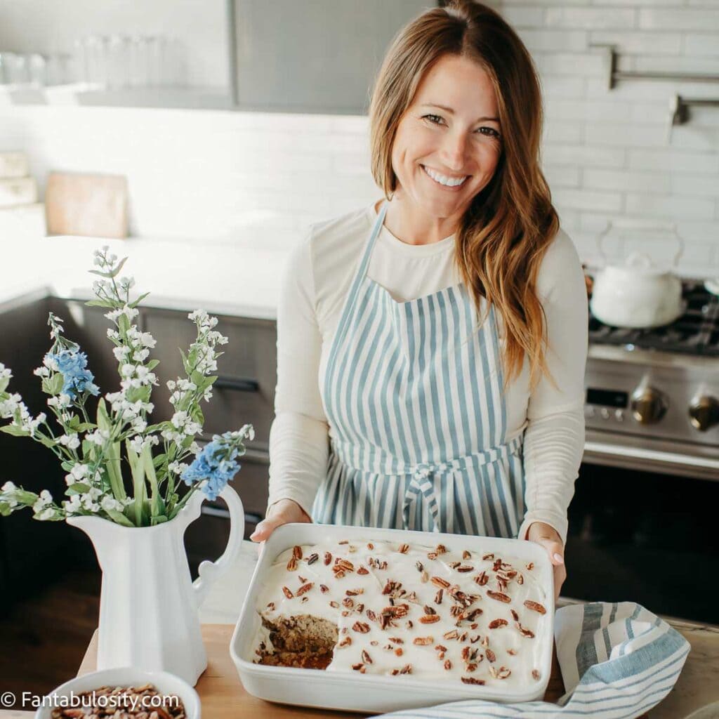 Jessica Burgess standing in kitchen holding a hummingbird cake.