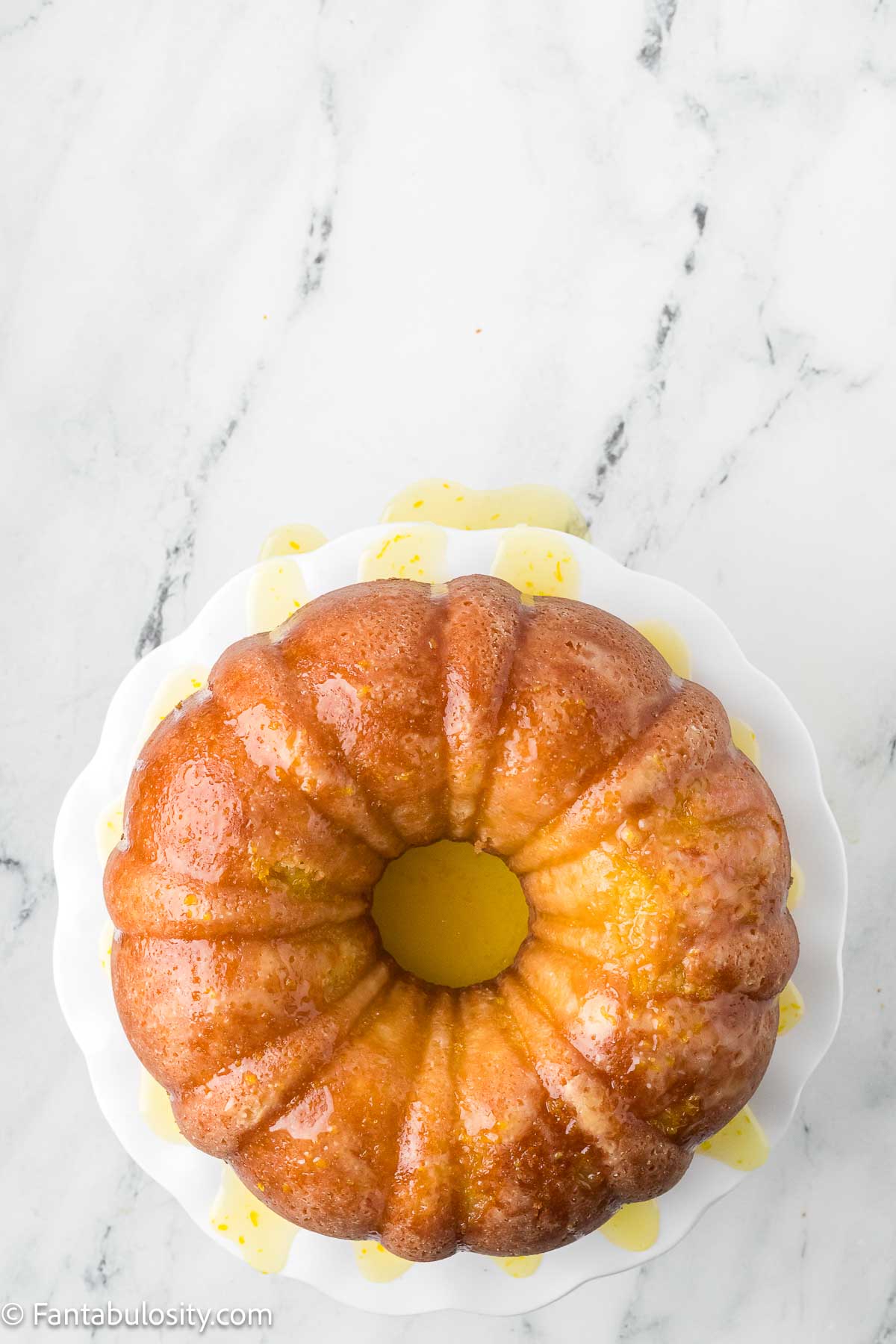 Orange glaze poured over bundt cake.