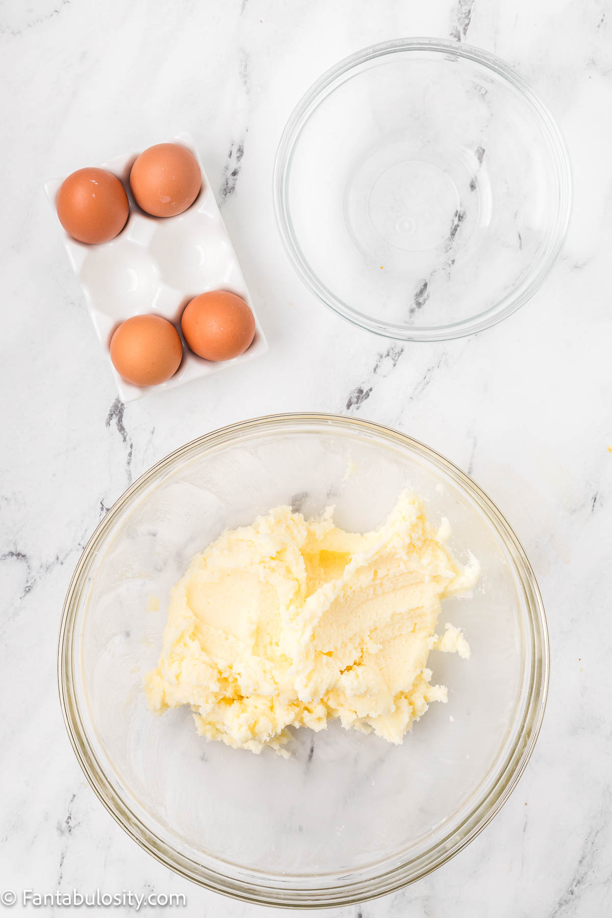 Sugar and butter creamed together in glass mixing bowl.