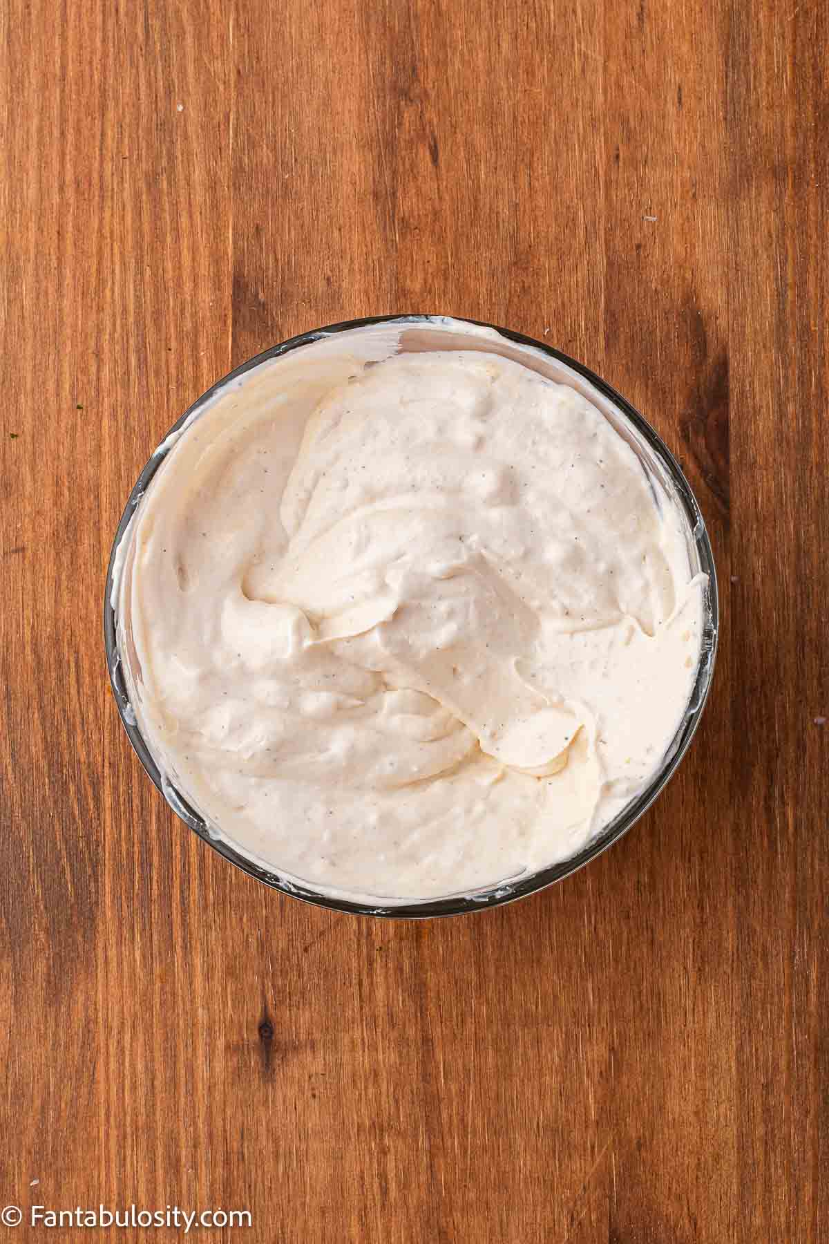 Roasted potato salad dressing mixed together in a mixing bowl.