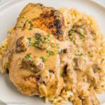 Smothered pork chop with mushroom gravy on top of rice in a plate.
