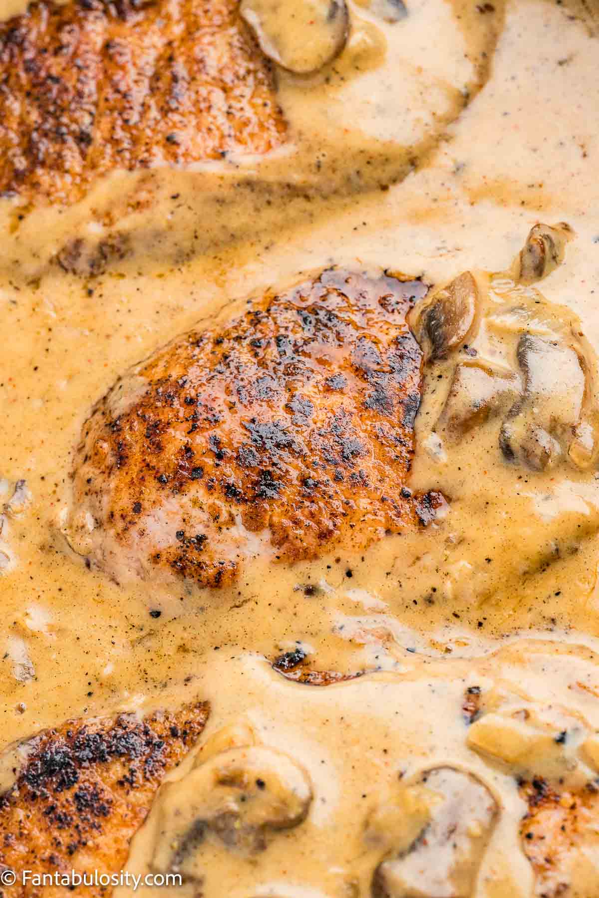 Smothered pork chops and gravy in skillet.