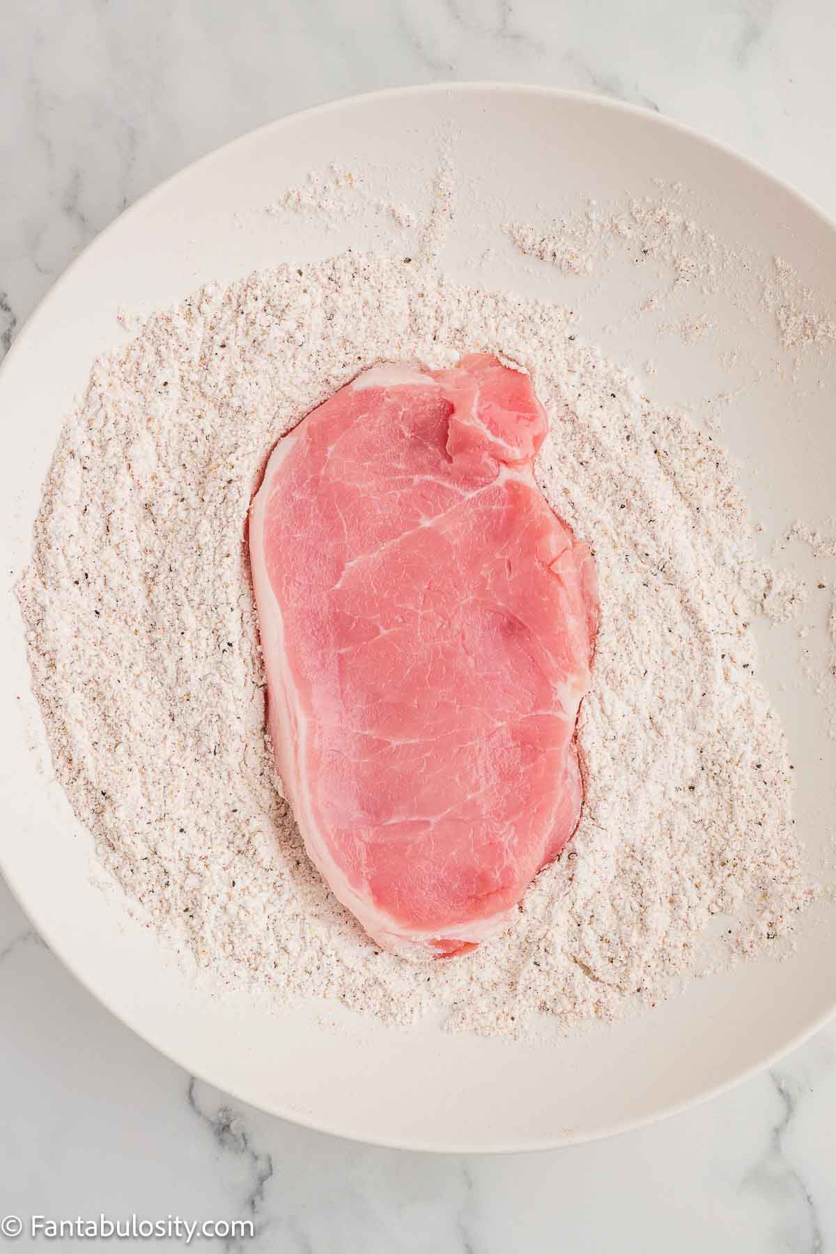 Pork chop dredged in flour and spice mixture.