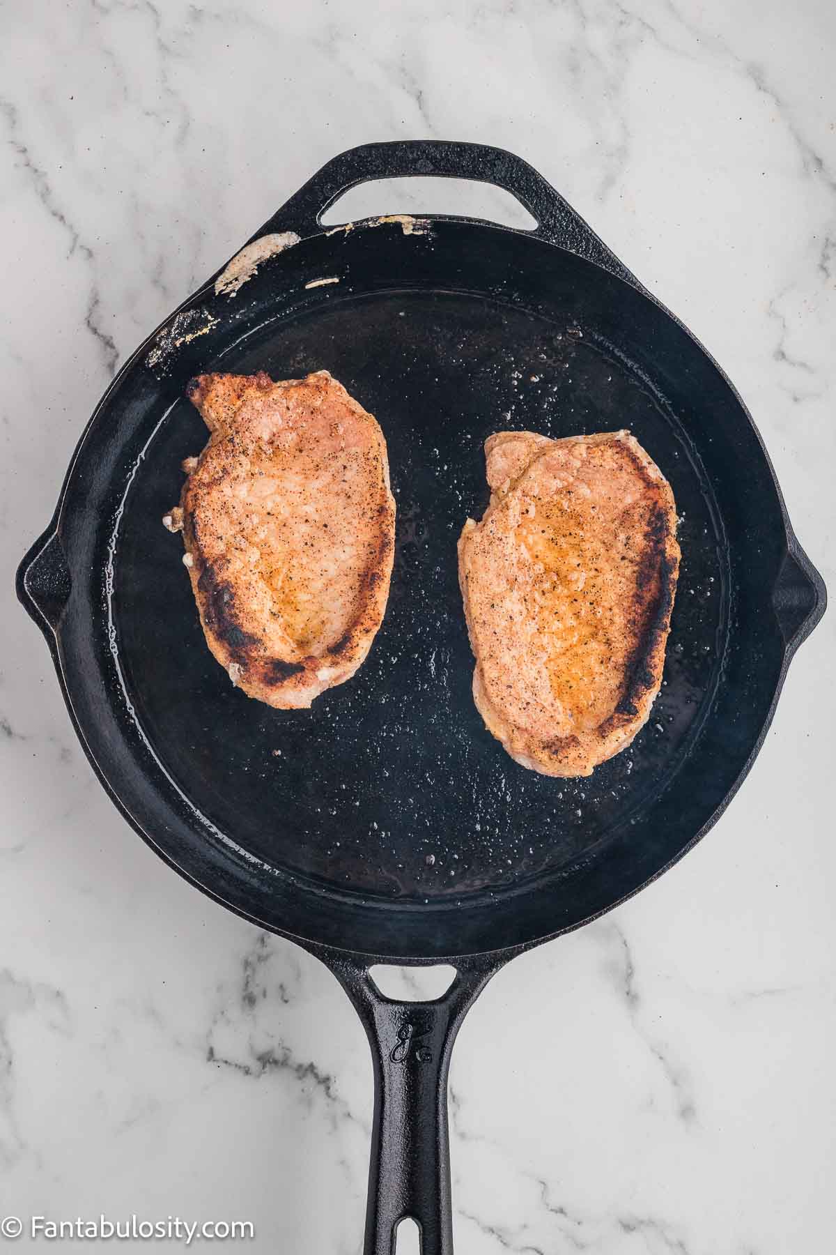 Pork chop seared in cast iron skillet.
