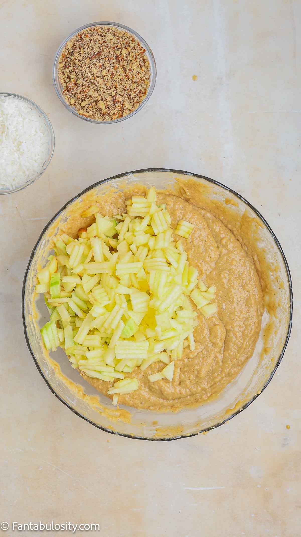 Apples added in to bread batter mixture in mixing bowl.