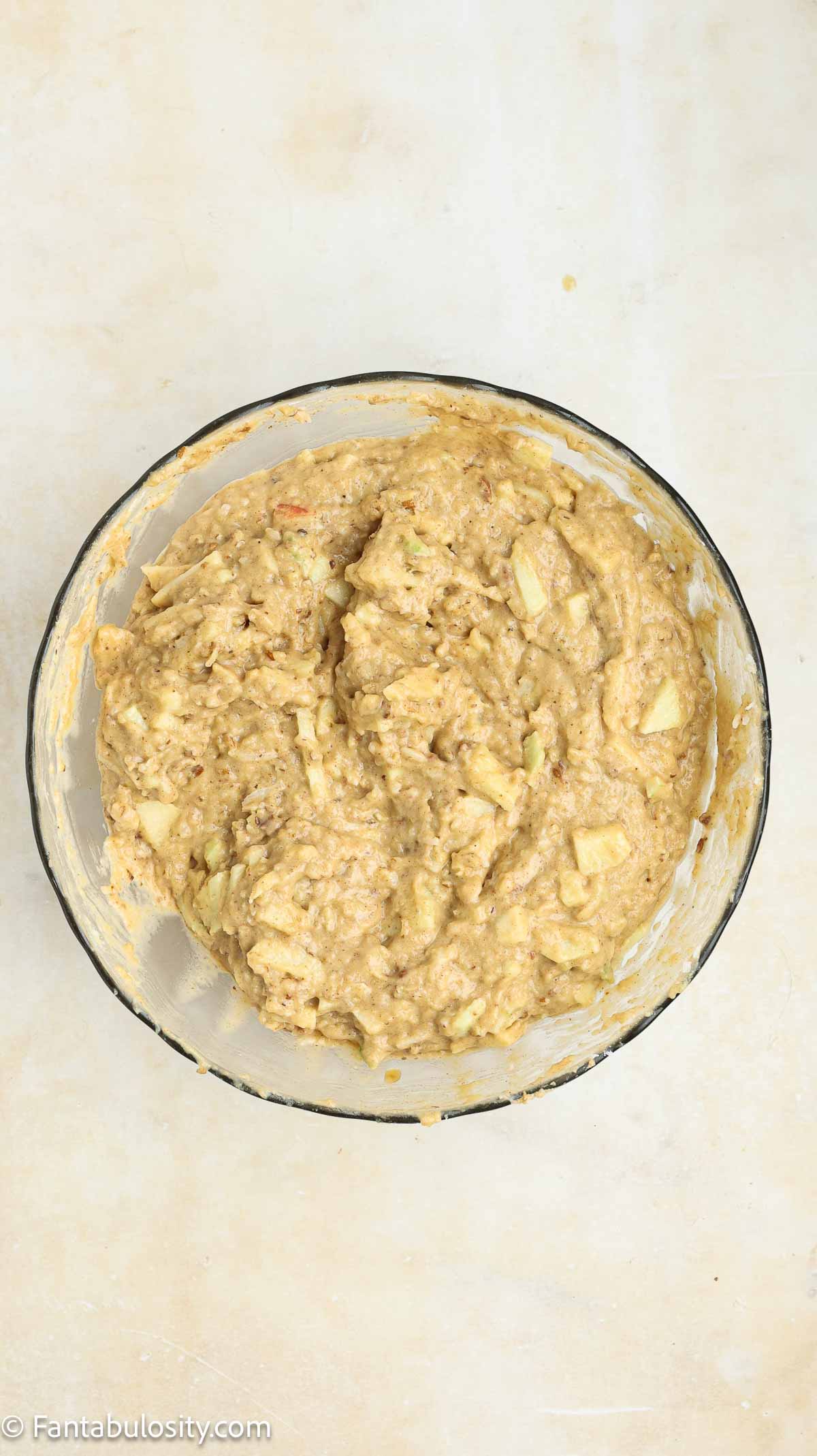 Apples added to flour and batter mixture in mixing bowl.