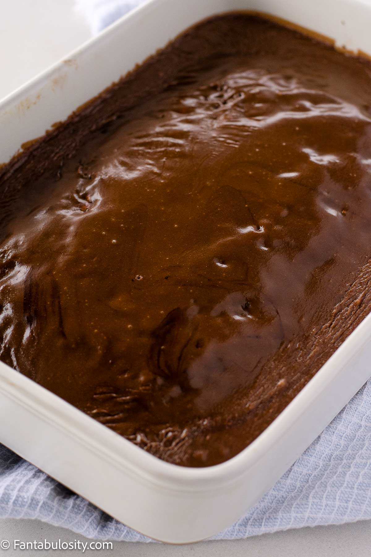 Chocolate Coca-Cola frosting poured on top of Coca-Cola cake in 9x13 baking dish.