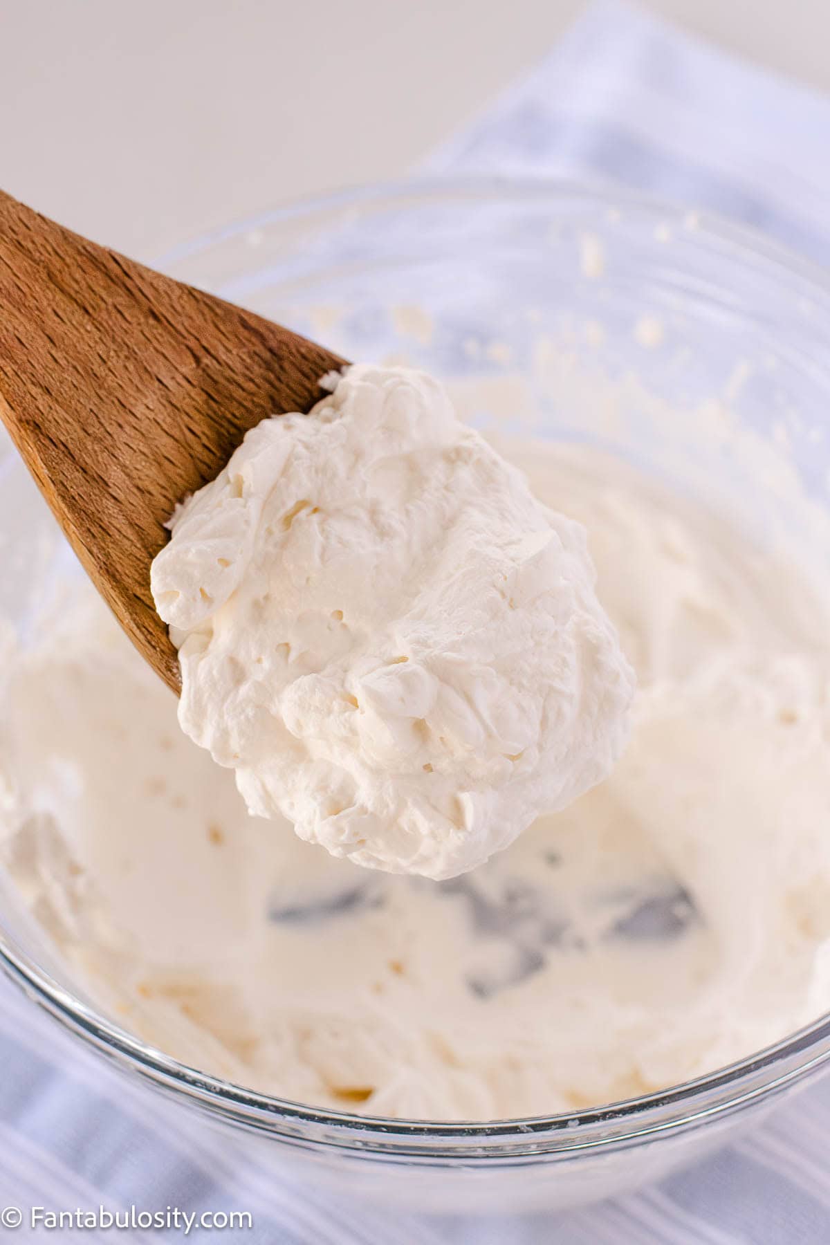 Wooden serving spoon dishing out homemade whipped cream.
