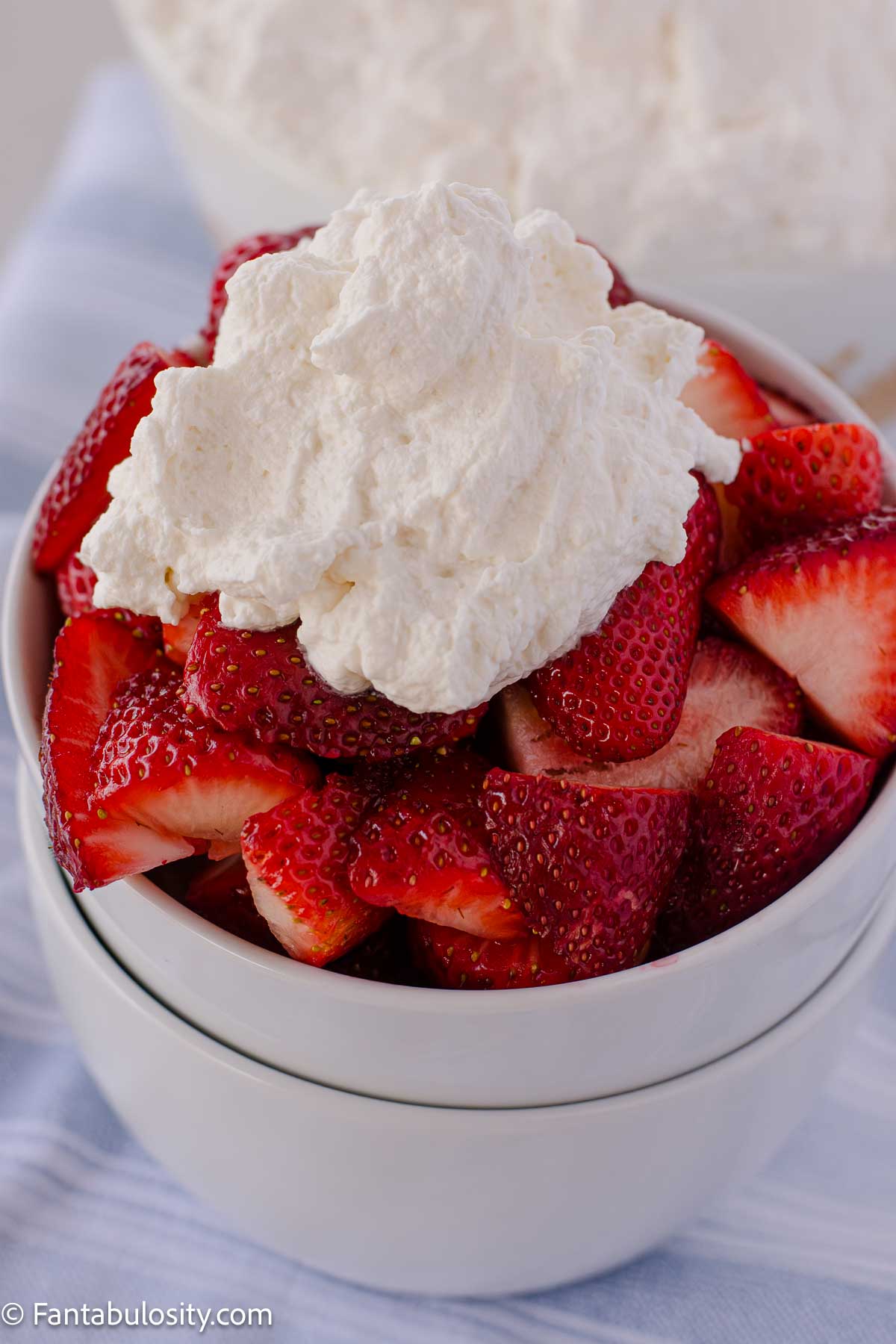 Bowl of strawberries topped with homemade whipped cream.