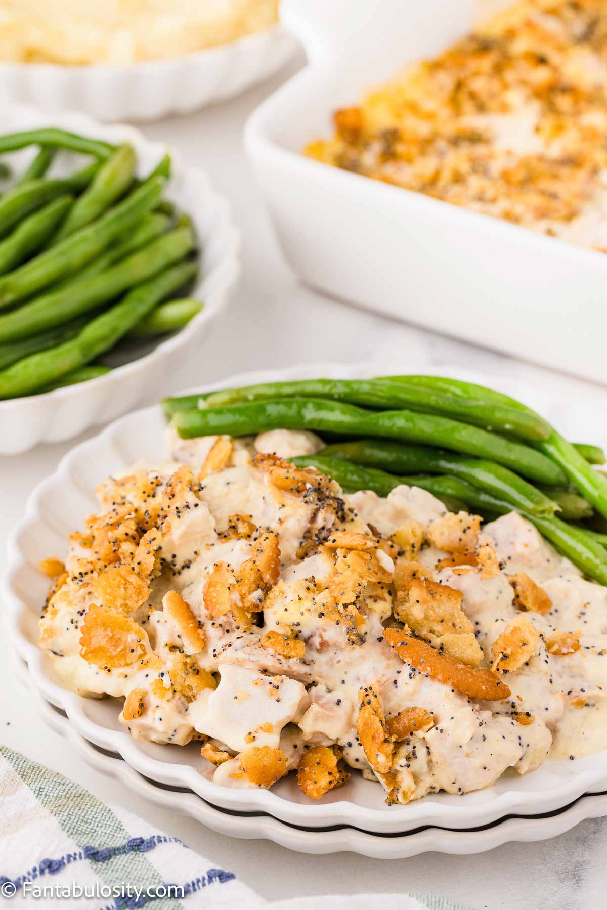 Poppy seed chicken casserole on a dinner plate, with green beans.