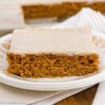 A slice of pumpkin sheet cake with brown butter frosting on a vintage plate.
