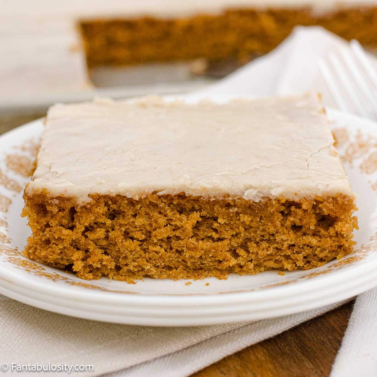 A slice of pumpkin sheet cake with brown butter frosting on a vintage plate.