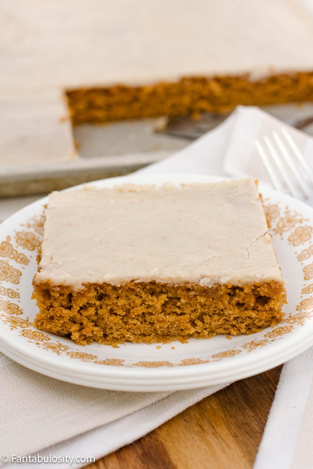 A slice of pumpkin sheet cake topped with brown butter frosting, sitting on vintage plate.
