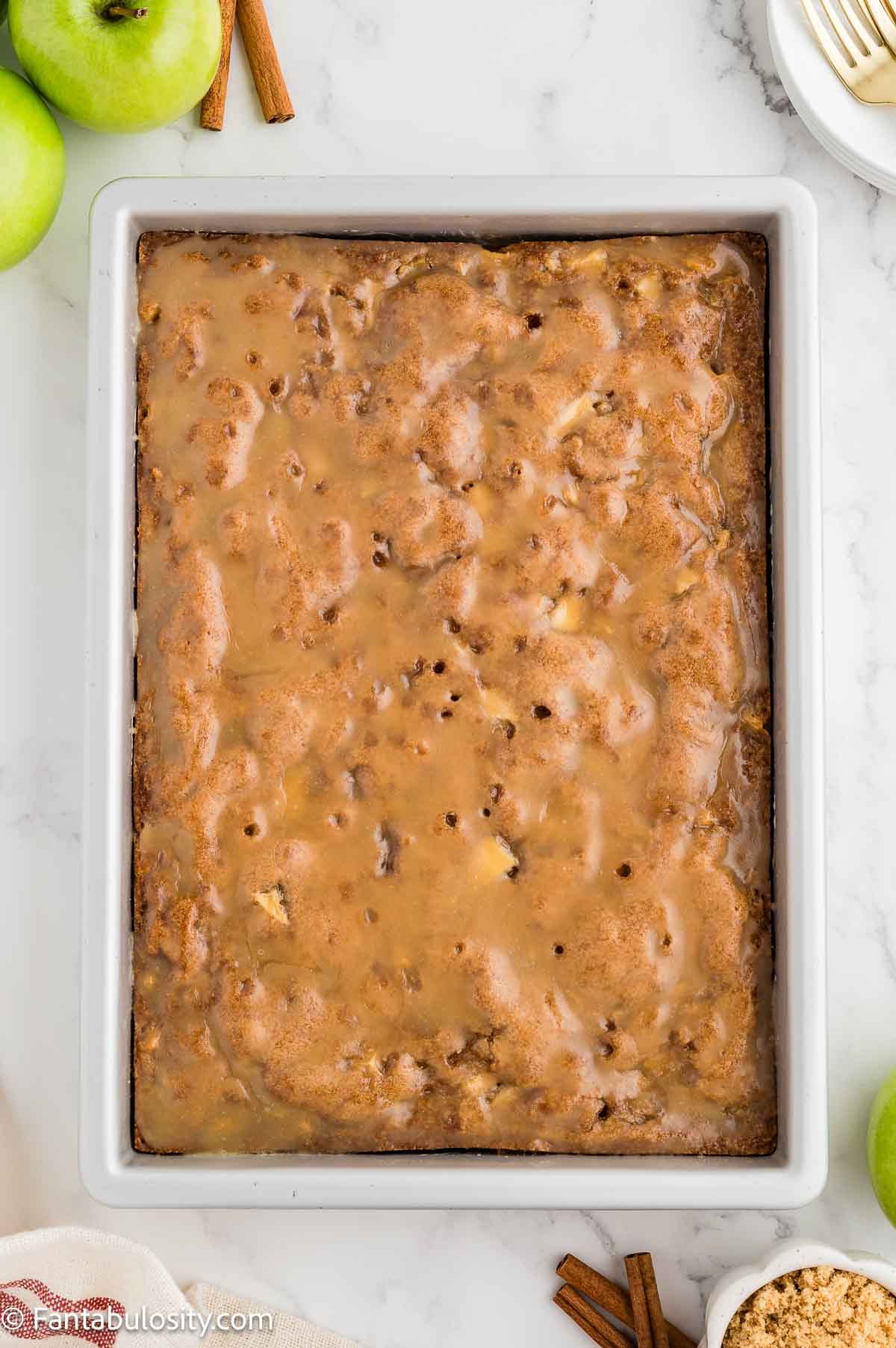 A pan of baked apple dapple cake covered in caramel glaze.