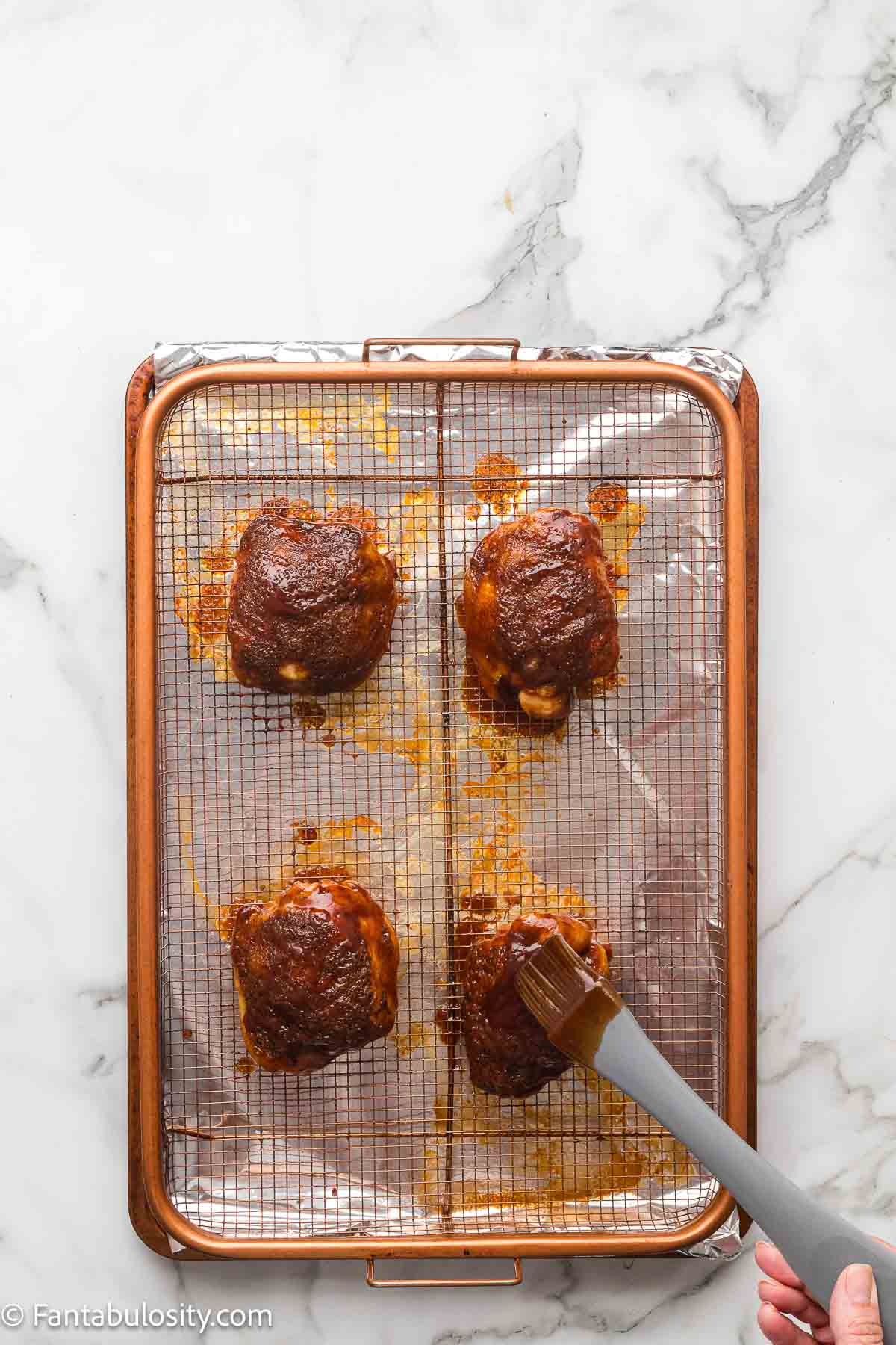 A second coat of BBQ glaze brushed onto the chicken thighs until glossy and caramelized.
