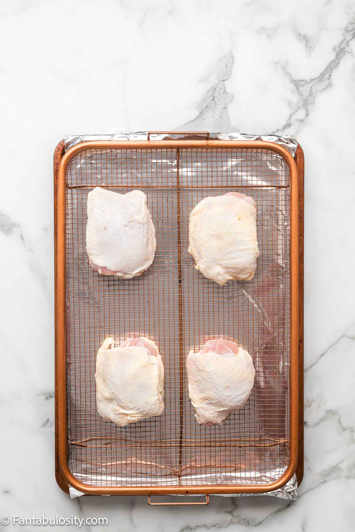 Raw chicken thighs patted dry and arranged skin side up on a wire rack in a foil-lined sheet pan.