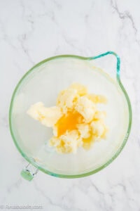 Eggs added to creamed butter and sugar in a glass mixing bowl.