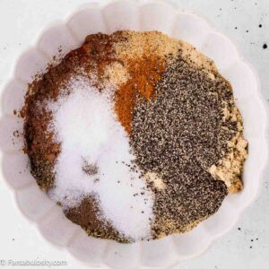Spices for homemade dry rub for ribs measured into a white bowl before mixing