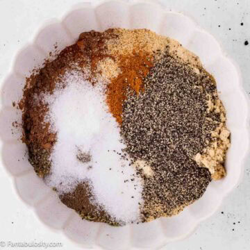 Spices for homemade dry rub for ribs measured into a white bowl before mixing