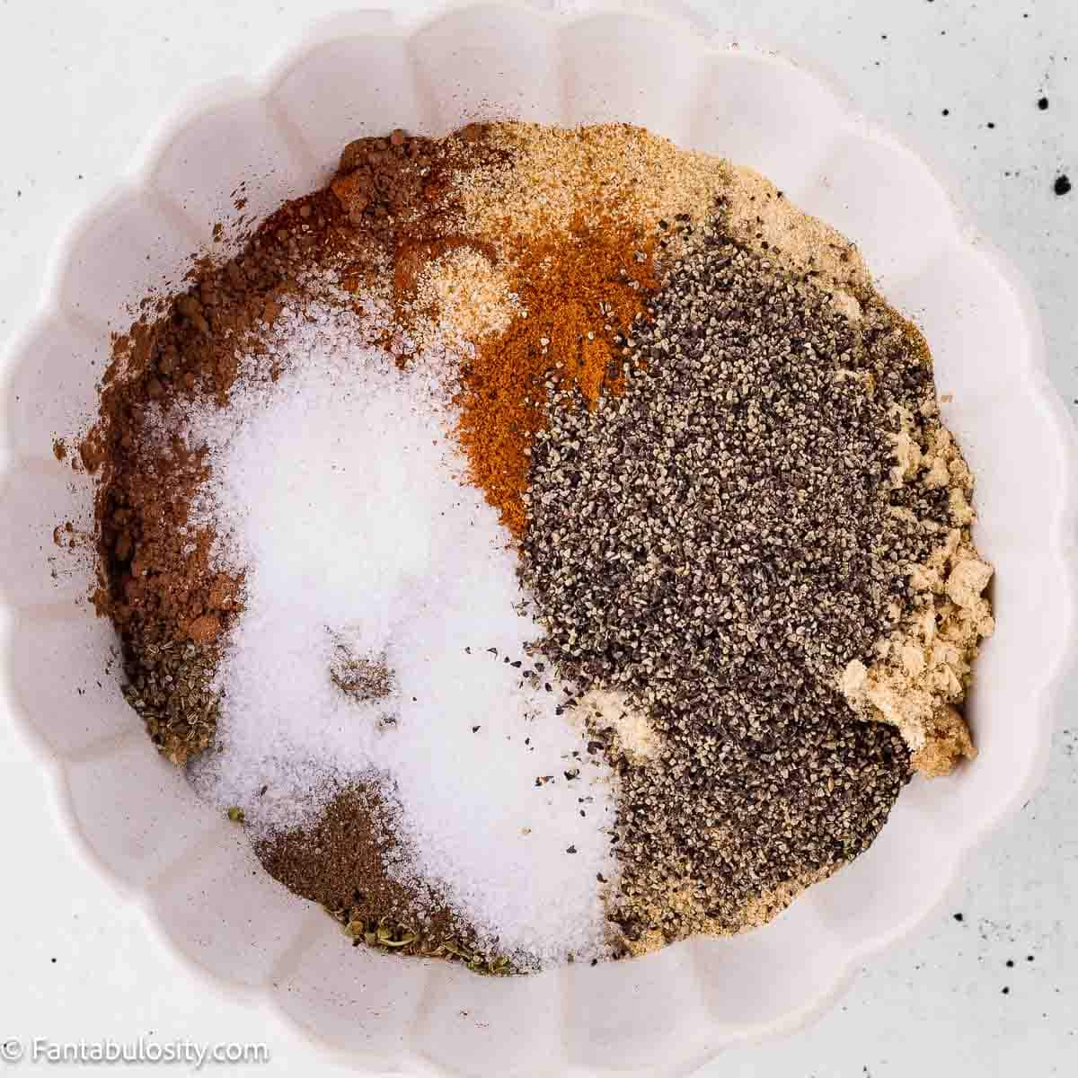 Spices for homemade dry rub for ribs measured into a white bowl before mixing
