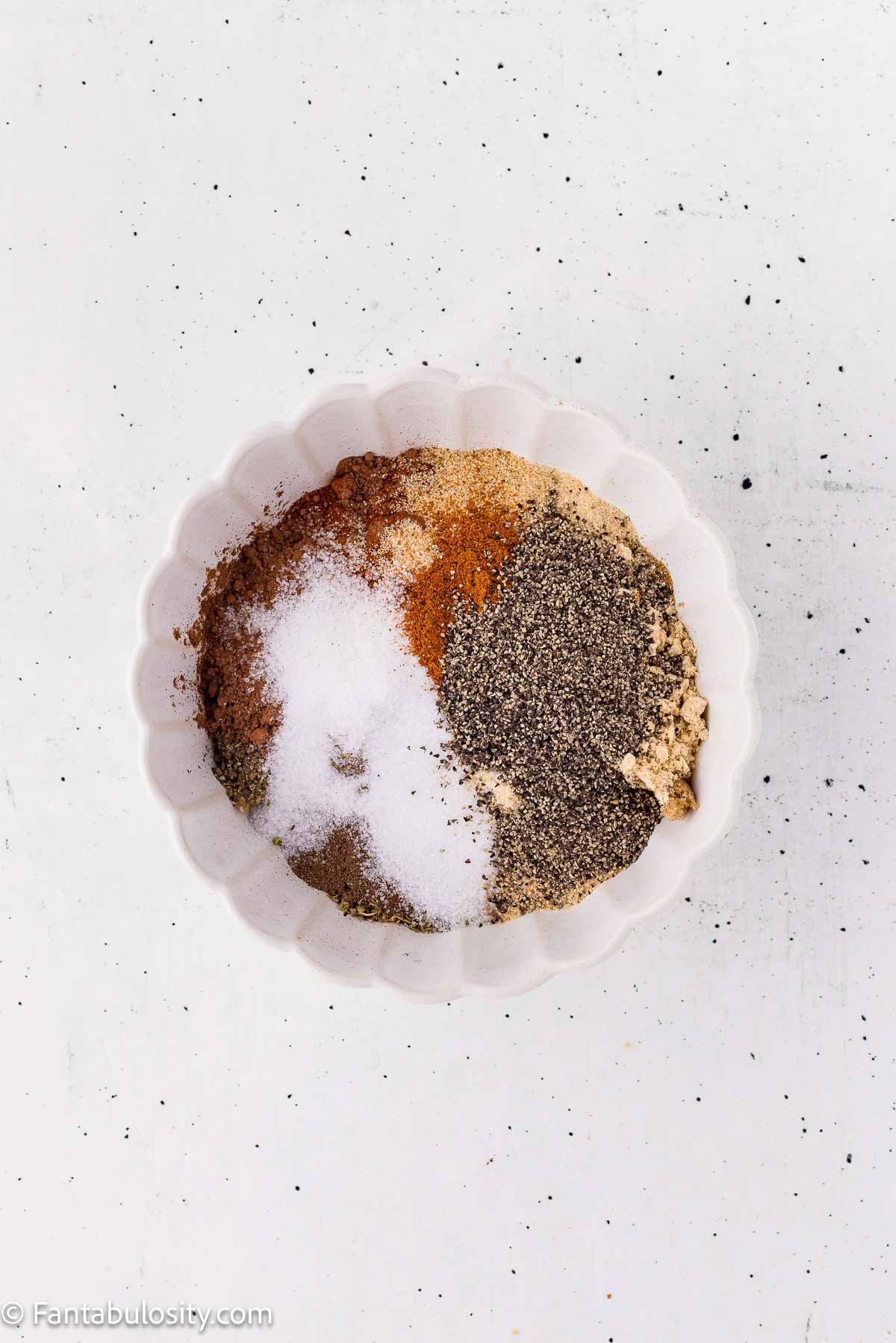 Unmixed spices for dry rub for ribs in a white bowl before stirring