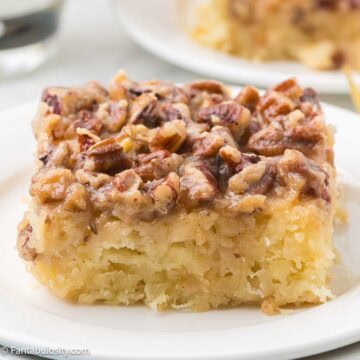 Slice of granny cake with brown sugar pecan topping on a white plate.