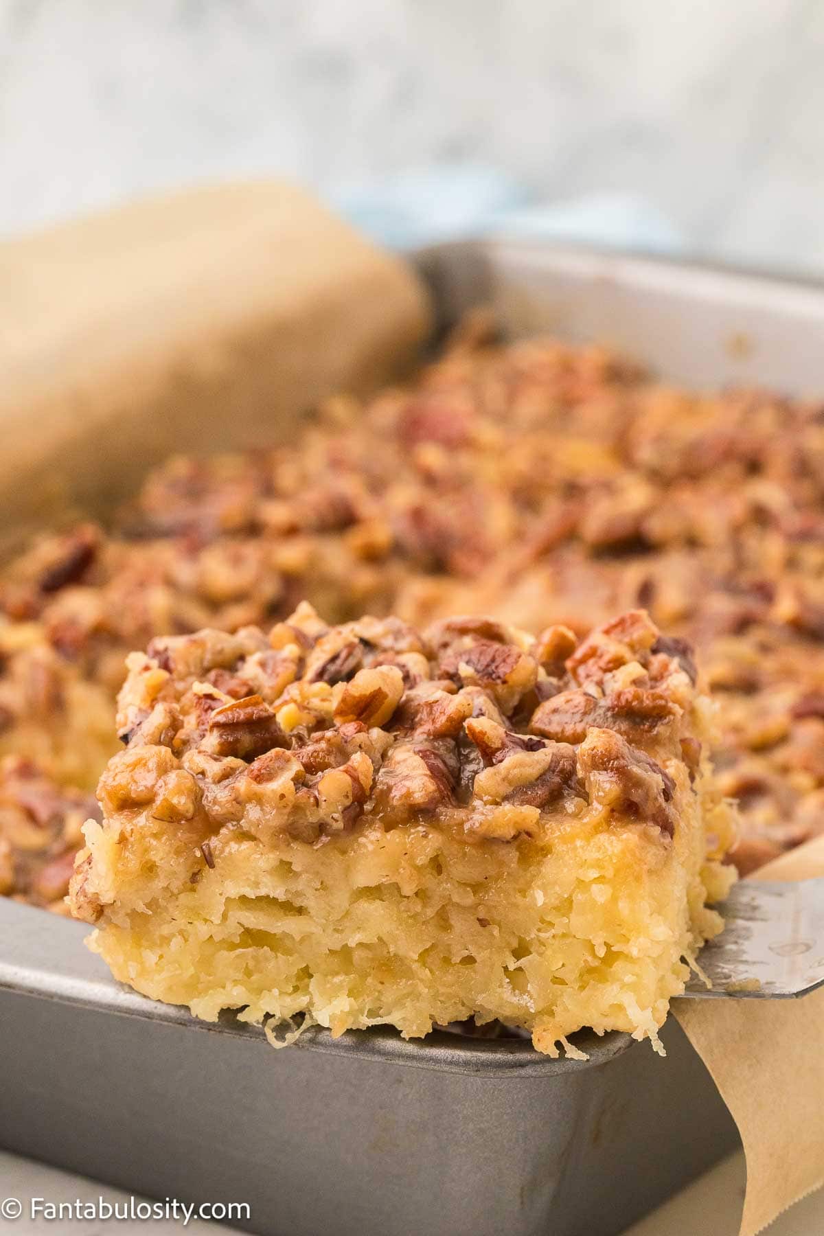Serving of granny cake lifted out of the baking pan with a spatula.