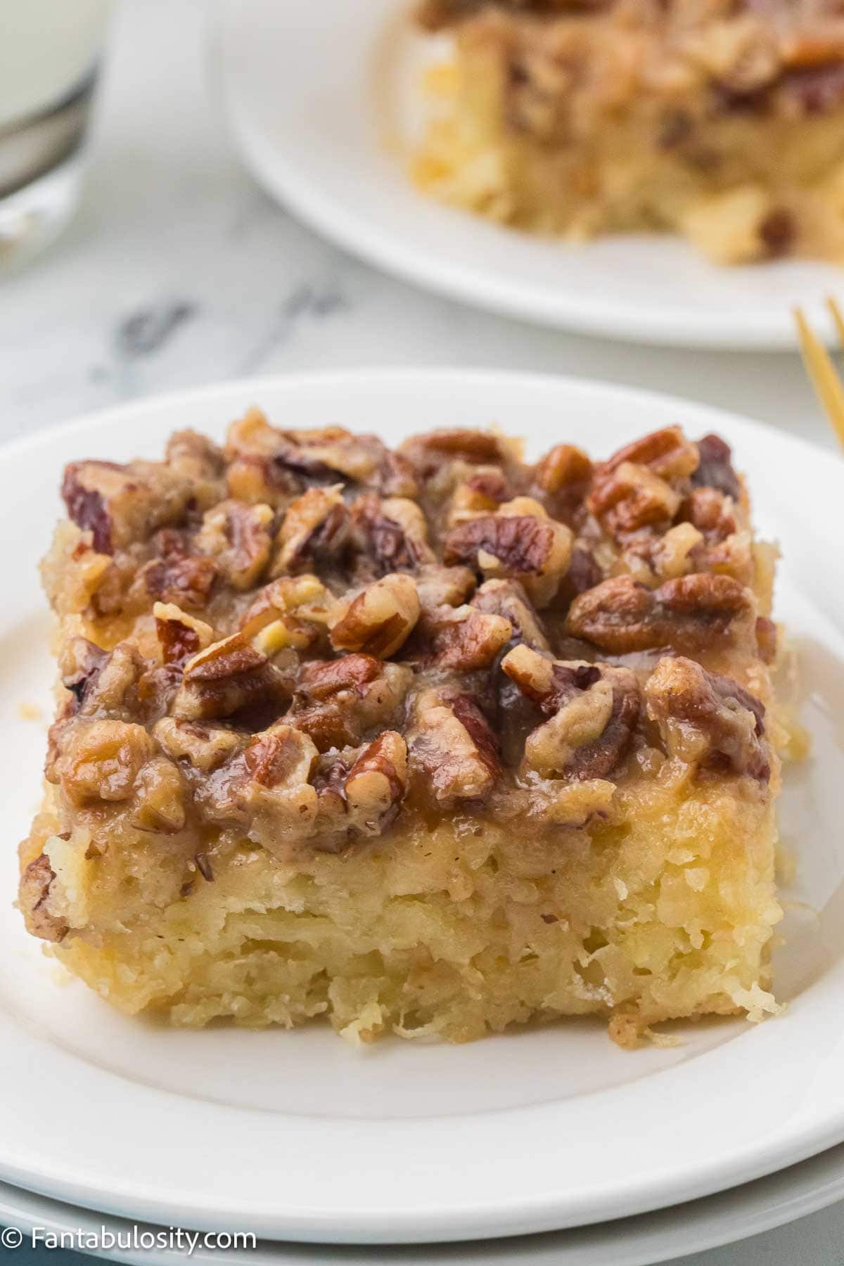 Slice of granny cake on a white plate showing the moist cake and pecan topping.
