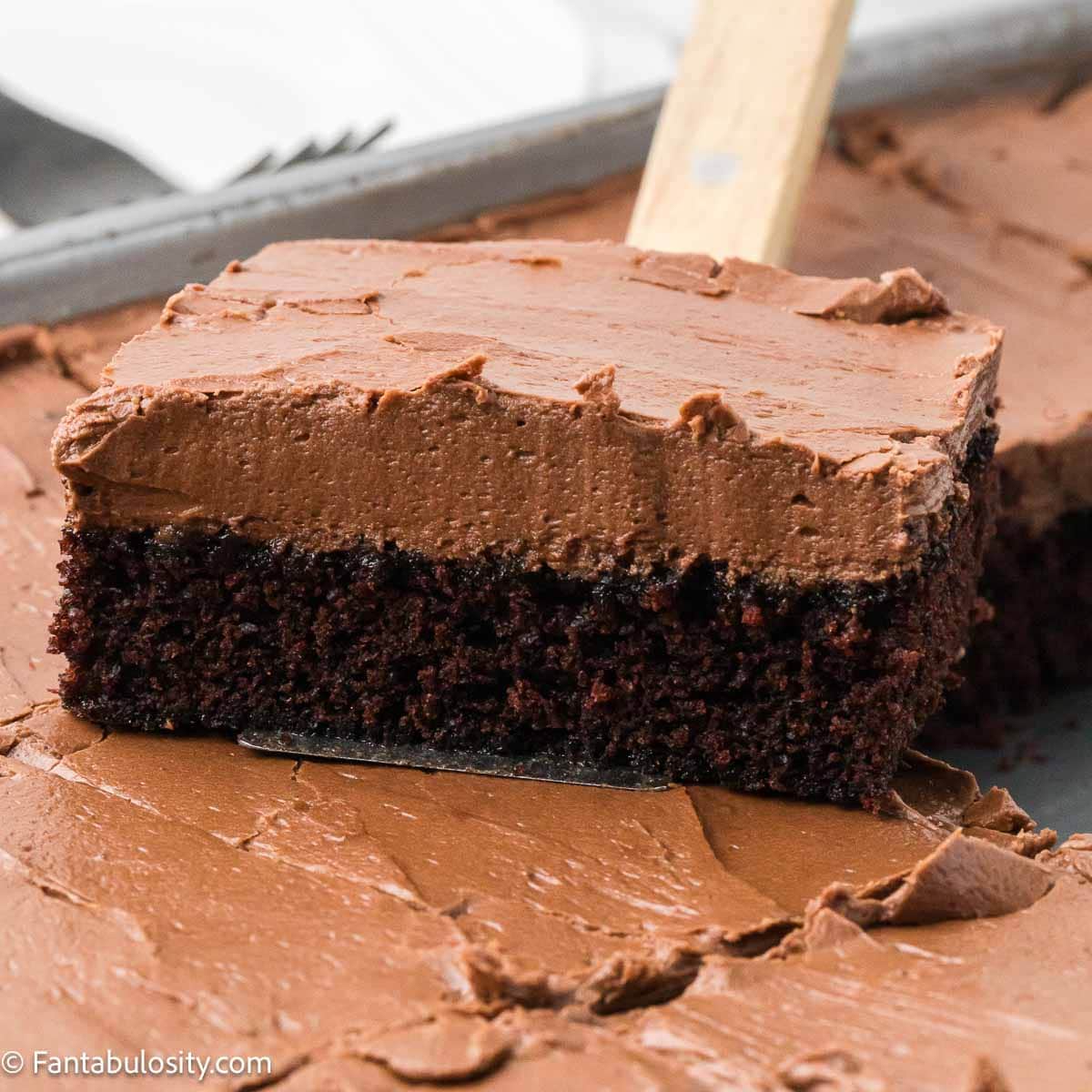Slice of chocolate mayonnaise cake with a thick layer of chocolate frosting lifted from the pan.