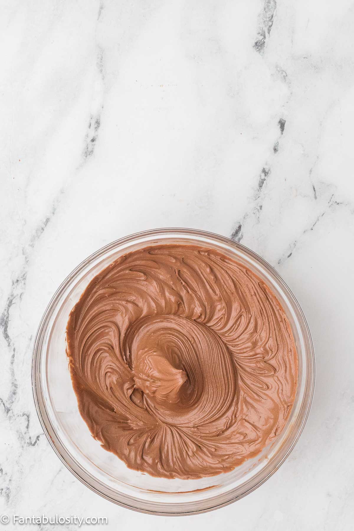 Smooth chocolate buttercream in a glass mixing bowl.