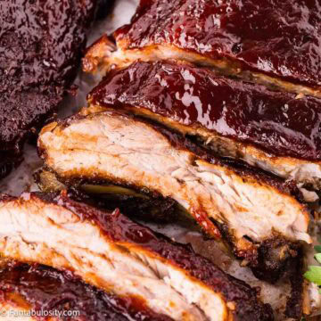 Sliced oven baked ribs on parchment showing tender meat under a dark BBQ glaze