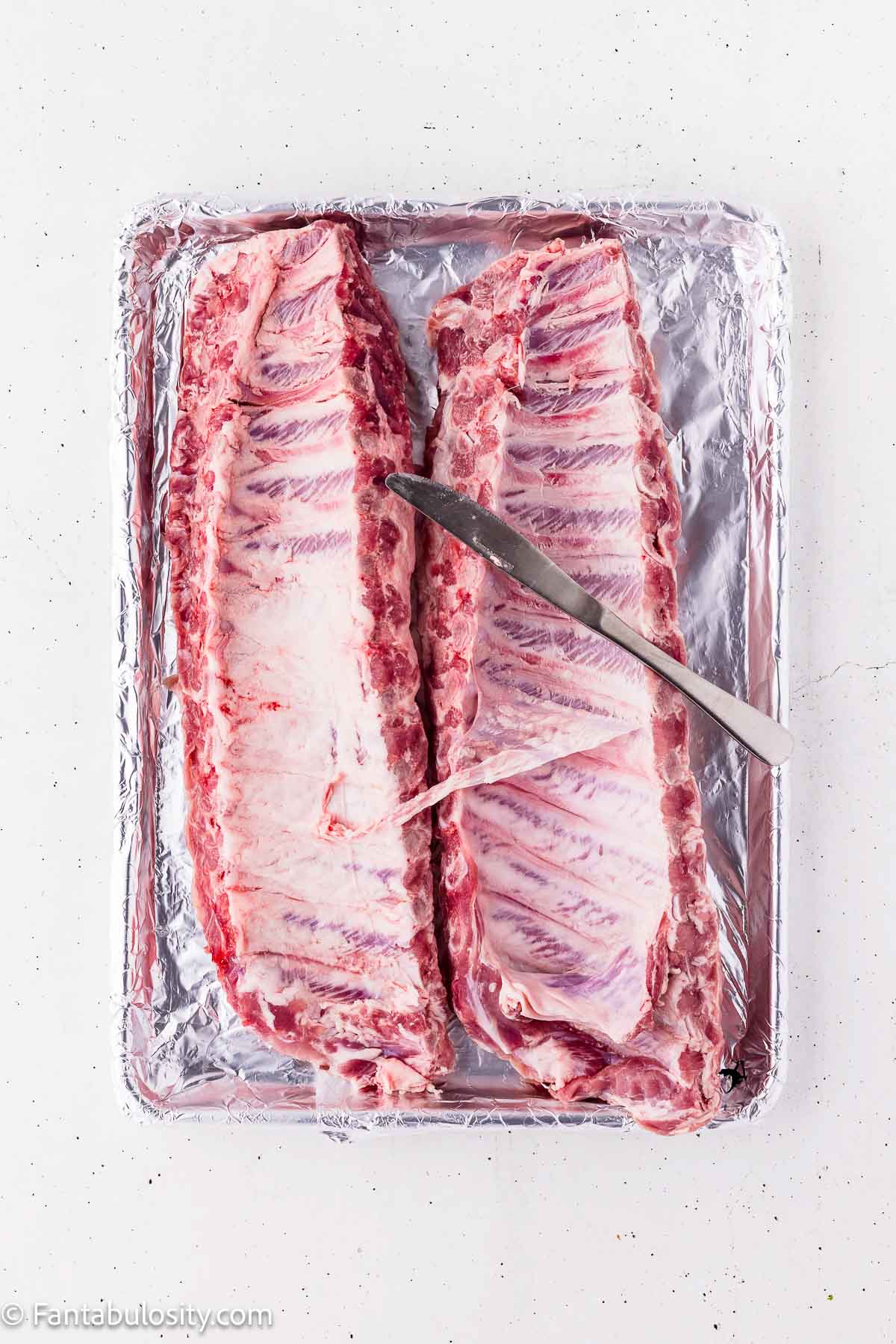 Loosening the membrane from the back of a rack of baby back ribs