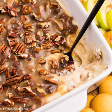 Close-up of pecan pie dip with a spoon showing the creamy base beneath the pecan topping.