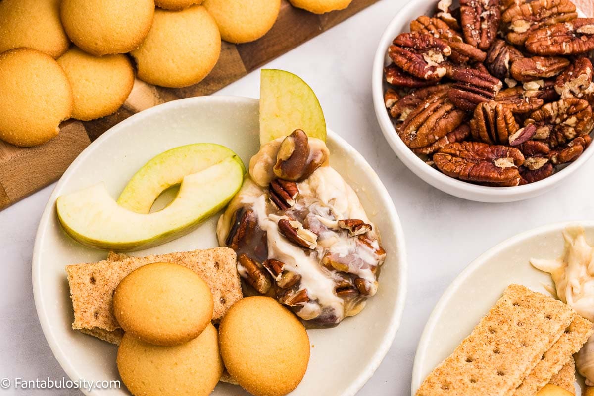 A serving of pecan pie dip on a plate with apple slices and vanilla wafers.