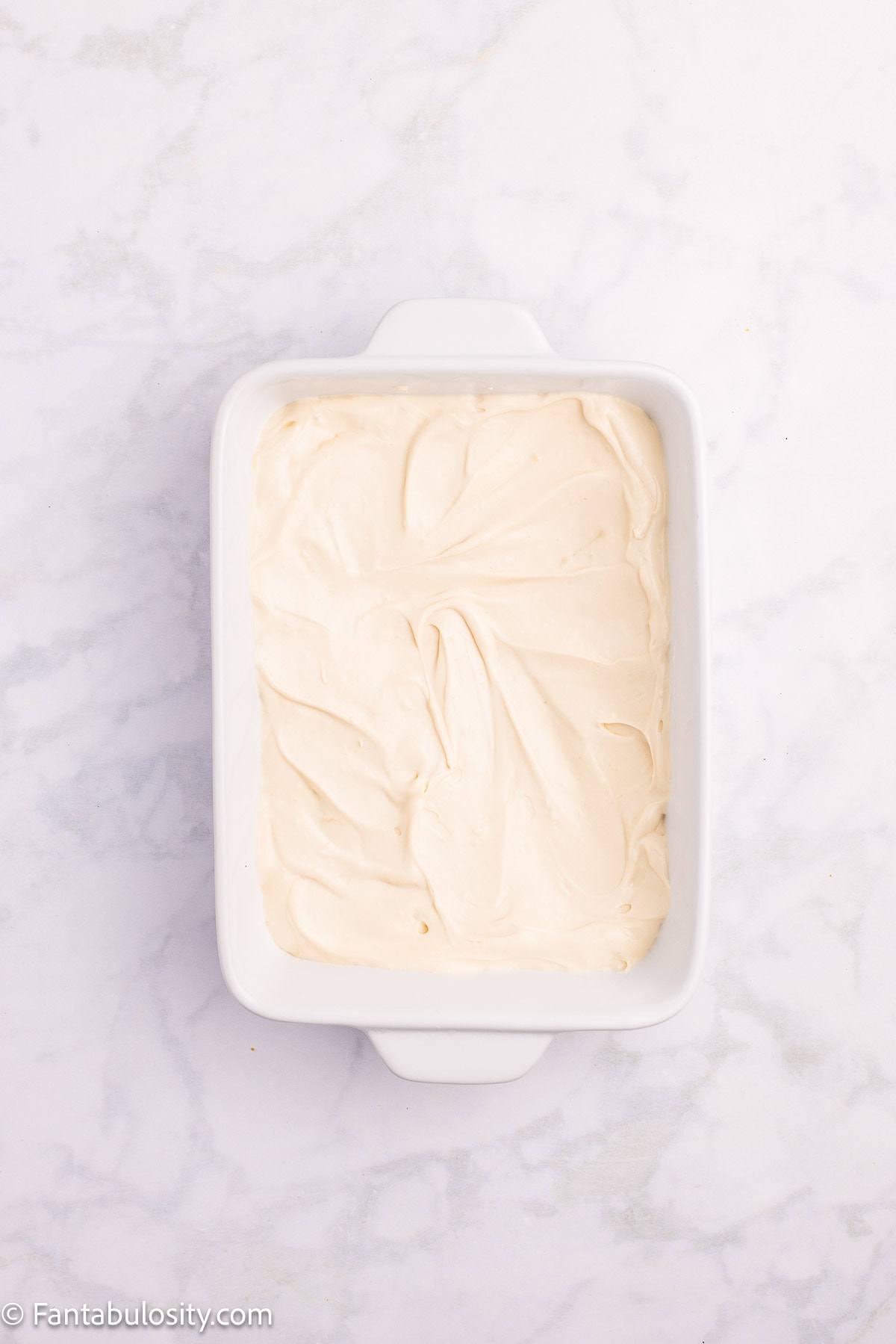 Cream cheese mixture spread evenly in a small white rectangular dish.
