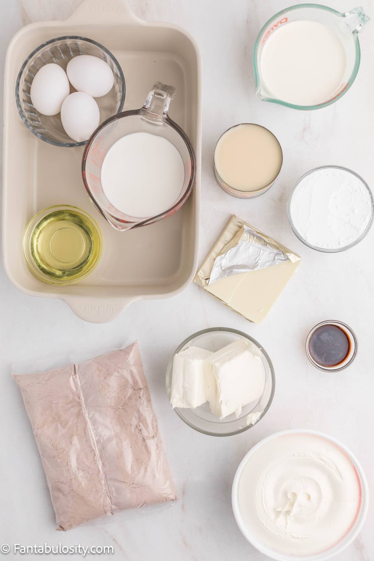 Ingredients for red velvet poke cake measured out on a marble counter.