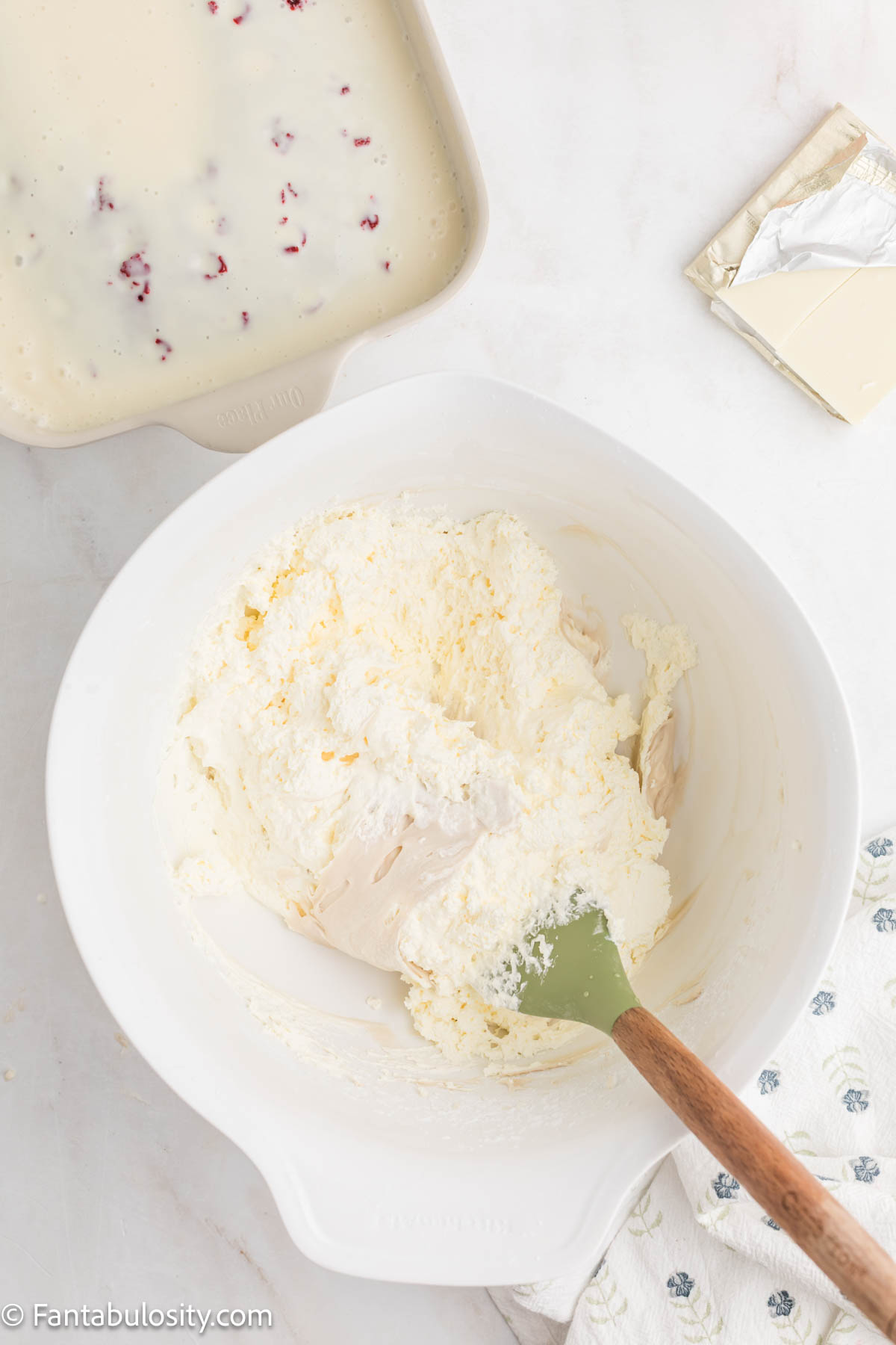 Cream cheese frosting with whipped topping folded in, in a white mixing bowl.